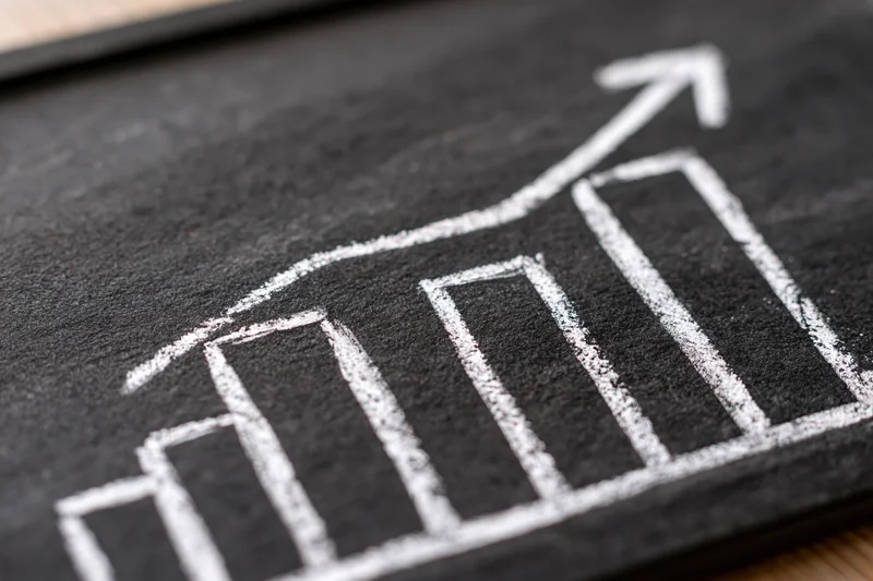 Hand-drawn chalk bar chart with upward arrow on blackboard