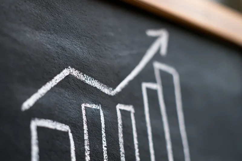 Hand-drawn chalk bar chart with upward arrow on blackboard
