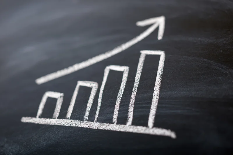 Hand-drawn chalk bar chart with upward arrow on blackboard