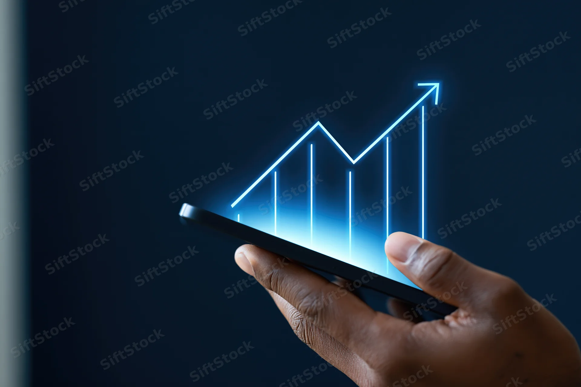 Hand holding smartphone with glowing blue upward graph emerging from screen against dark background