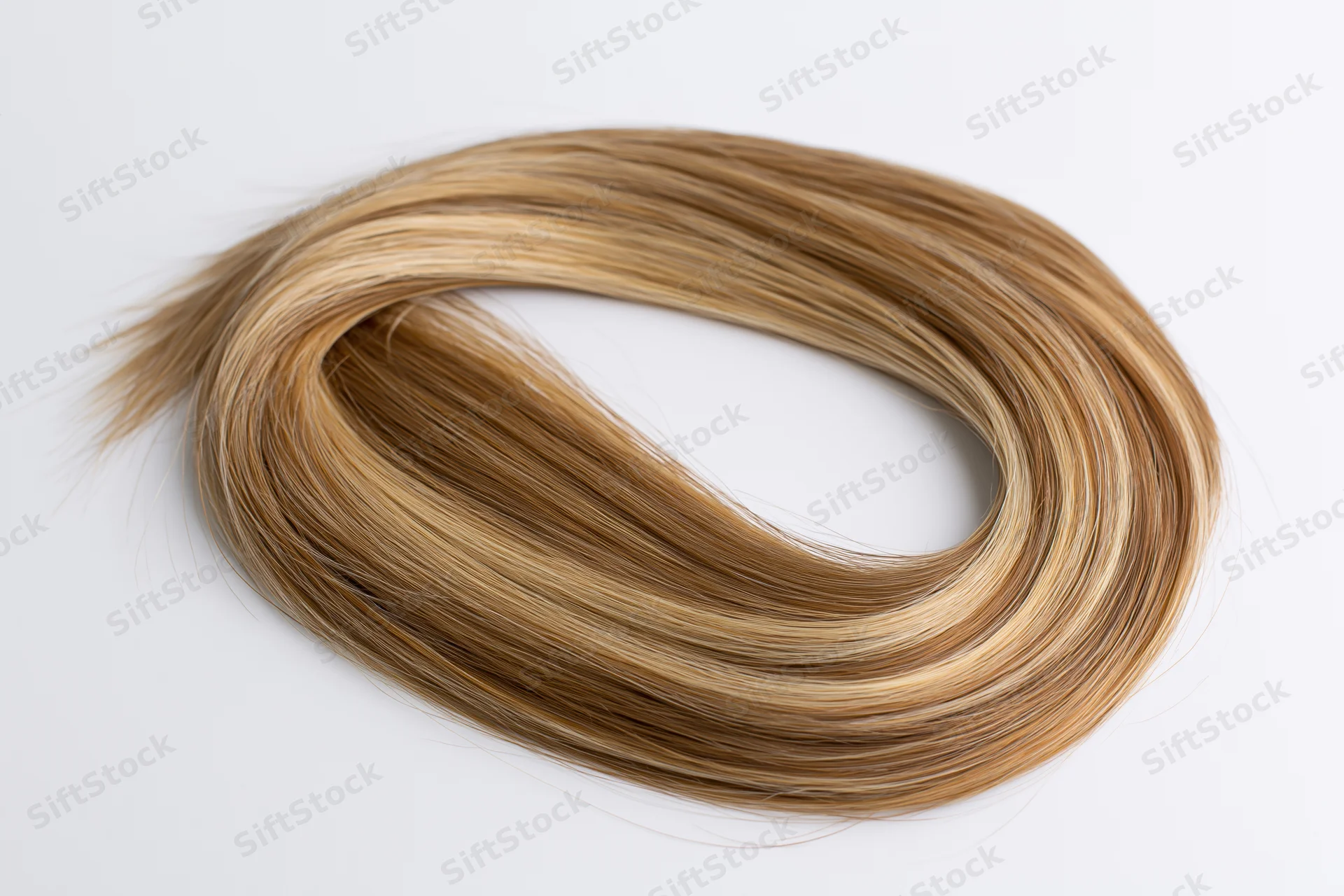 Loose curl of blonde human hair extension laid flat on white background