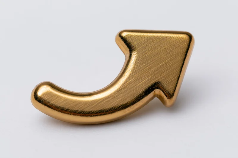 Polished gold metallic upward-curving arrow symbol isolated on white background