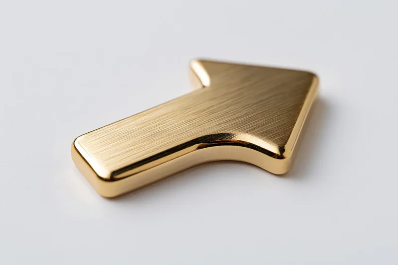 Polished gold metallic arrow pointing upward on white surface