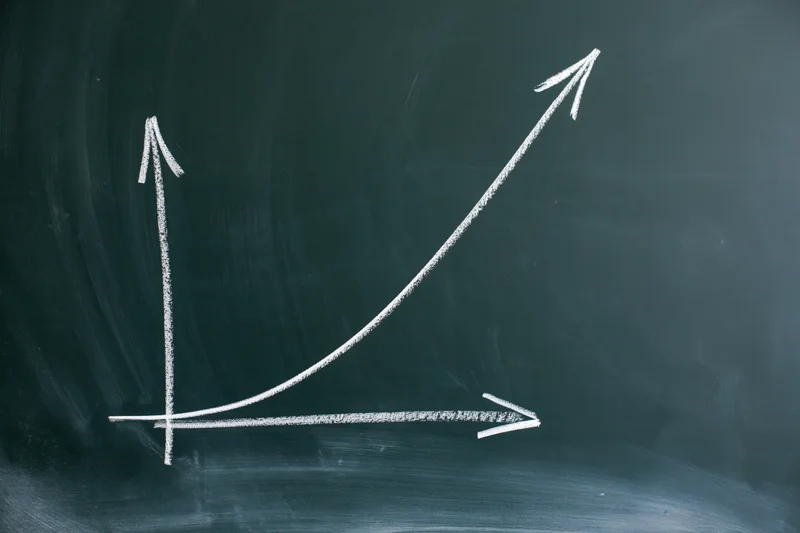 Exponential growth curve drawn in white chalk on a blackboard