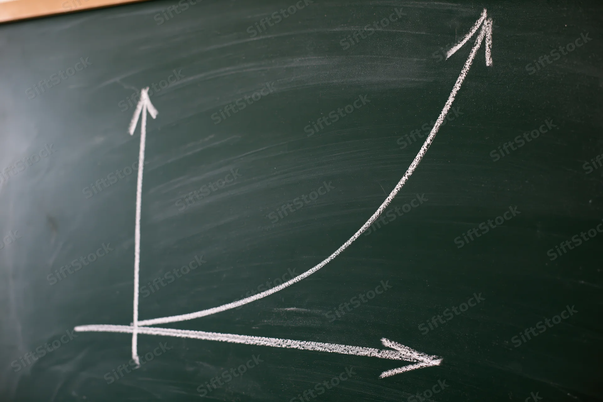 Exponential growth curve drawn in white chalk on a blackboard