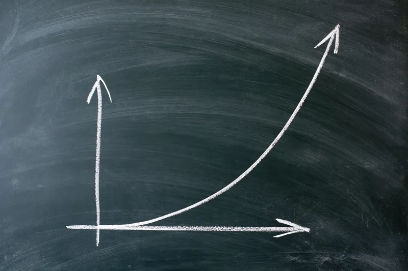 Exponential growth curve drawn in white chalk on a blackboard