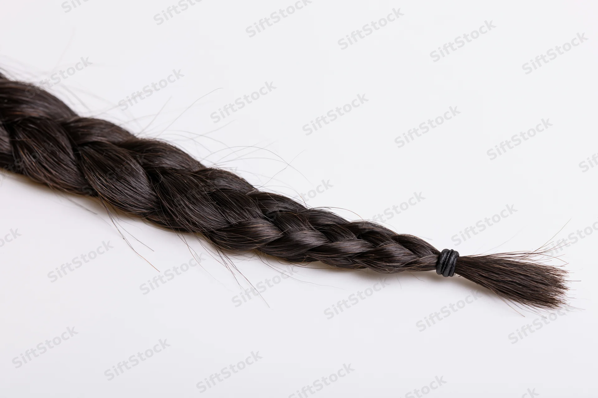Dark brown-black hair braid laid flat diagonally on white background