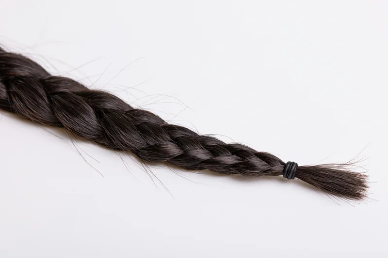 Dark brown-black hair braid laid flat diagonally on white background
