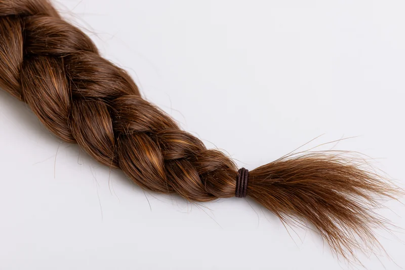 Thick brown french braid lying horizontally on white background