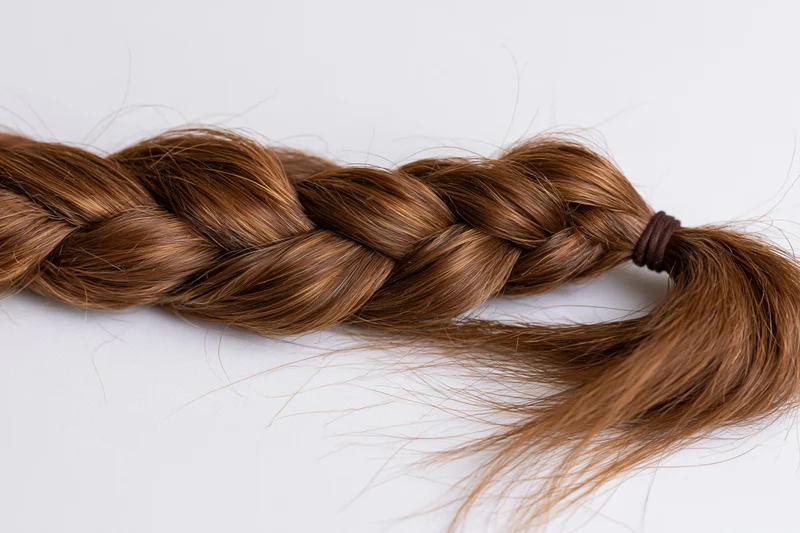 Thick brown french braid lying horizontally on white surface