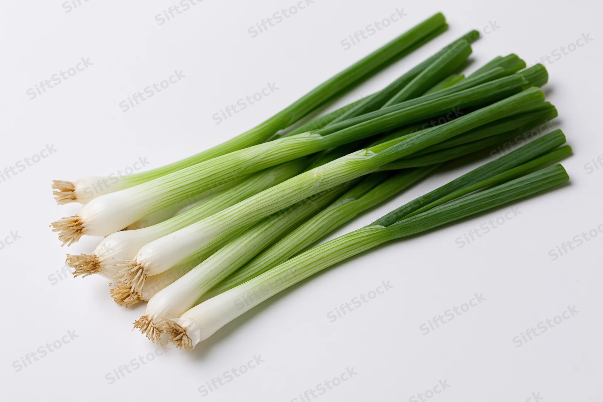 A small bunch of fresh green onions with white bulb ends arranged on a white surface