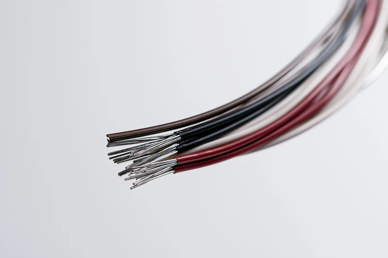 Bundle of thin electrical wires with stripped ends fanning apart against white background