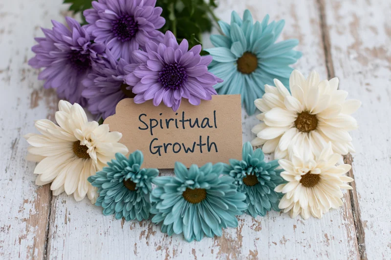 Colorful daisies arranged around a kraft tag reading spiritual growth on a weathered wooden surface