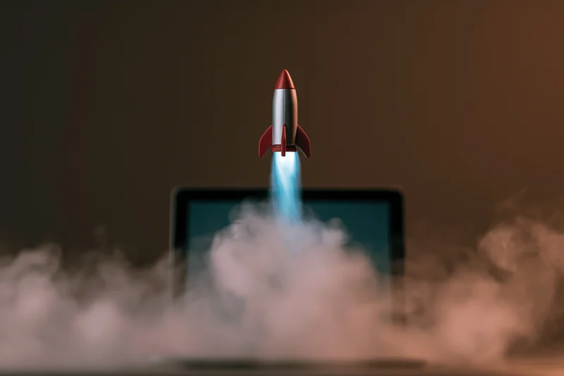 Small rocket launching from laptop screen surrounded by smoke