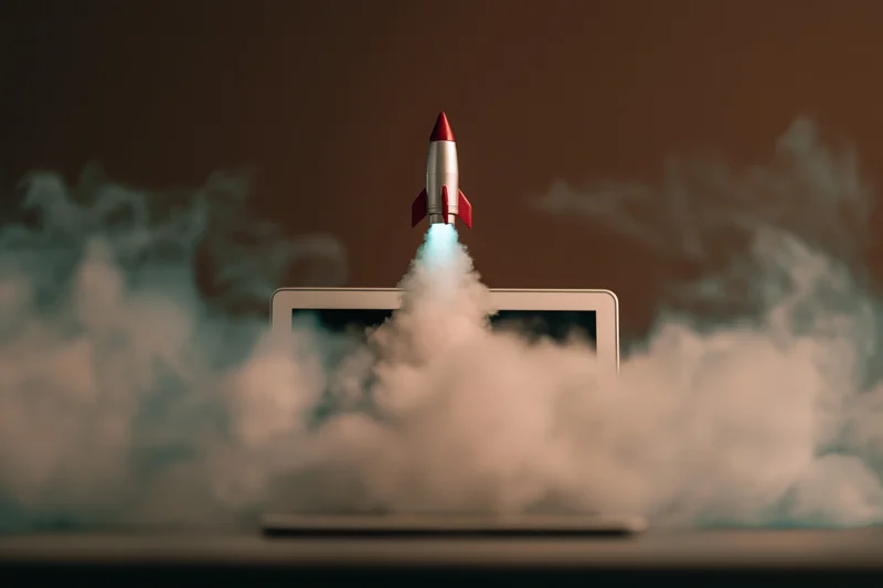 Small rocket launching from laptop screen surrounded by smoke