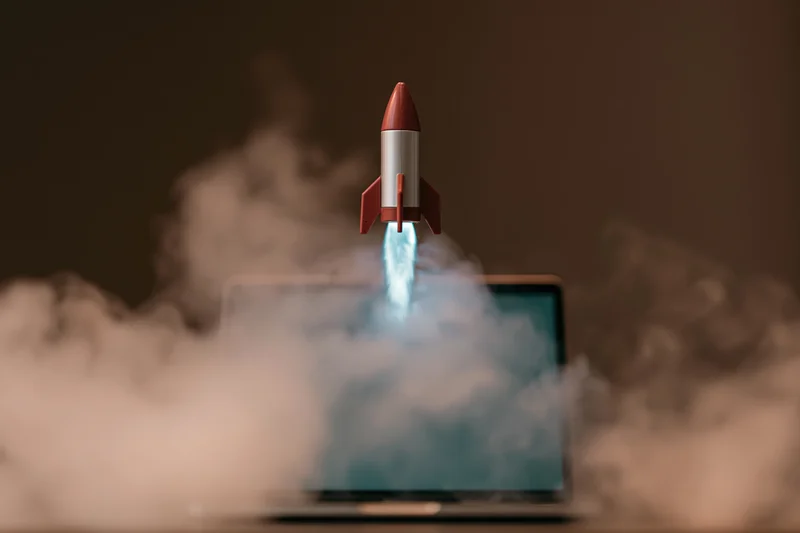 Small rocket launching from laptop screen surrounded by smoke