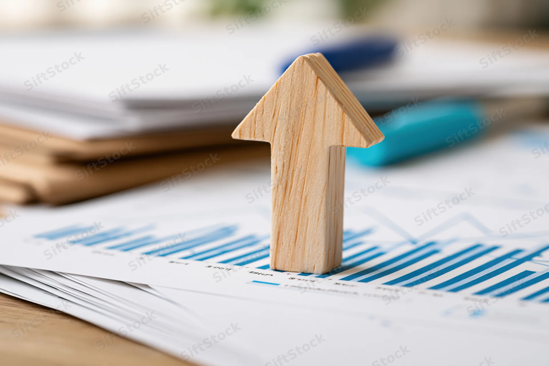 Wooden arrow pointing upward on financial charts on office desk