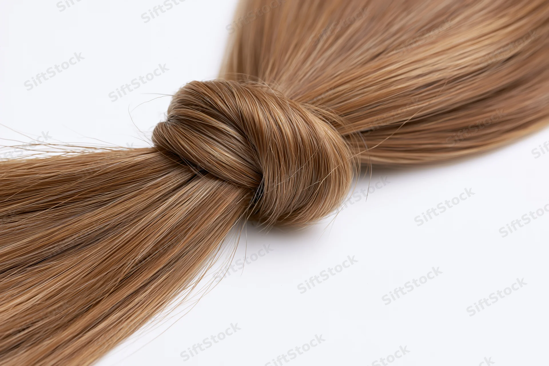 Smooth light brown hair strand twisted into a loose loop on white background