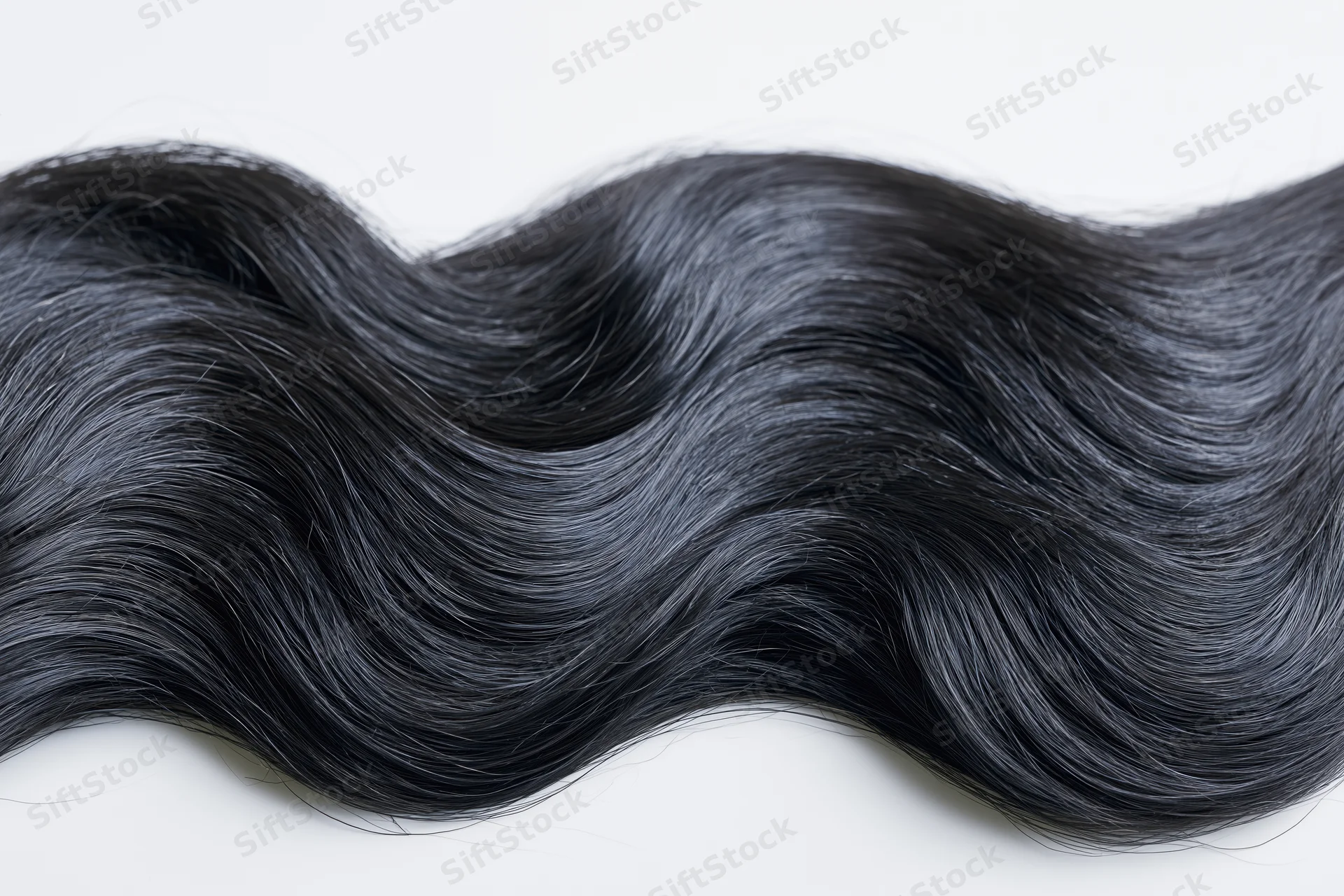 Thick wavy black hair lock laid flat on white background