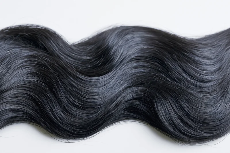 Thick wavy black hair lock laid flat on white background