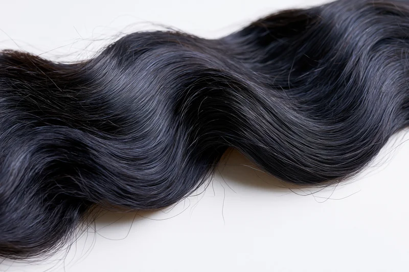 Thick wavy black hair lock laid flat on white background