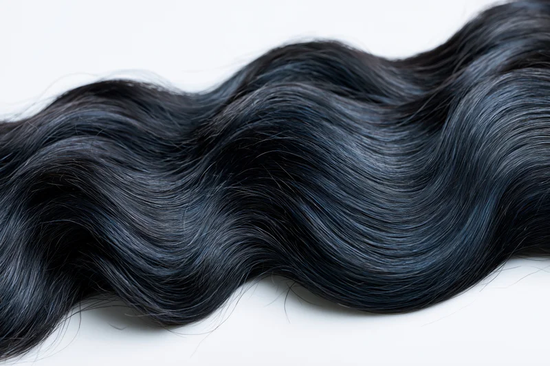 Thick wavy black hair lock laid flat on white background