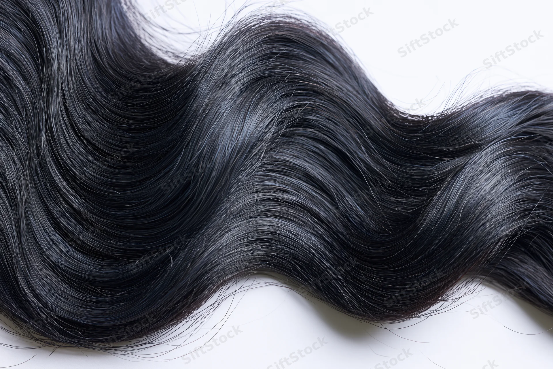 Thick wavy black hair lock laid flat on white background