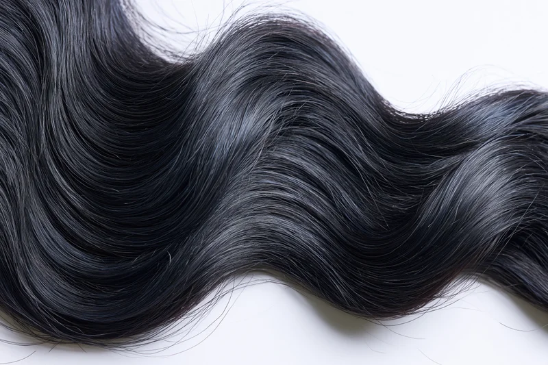 Thick wavy black hair lock laid flat on white background