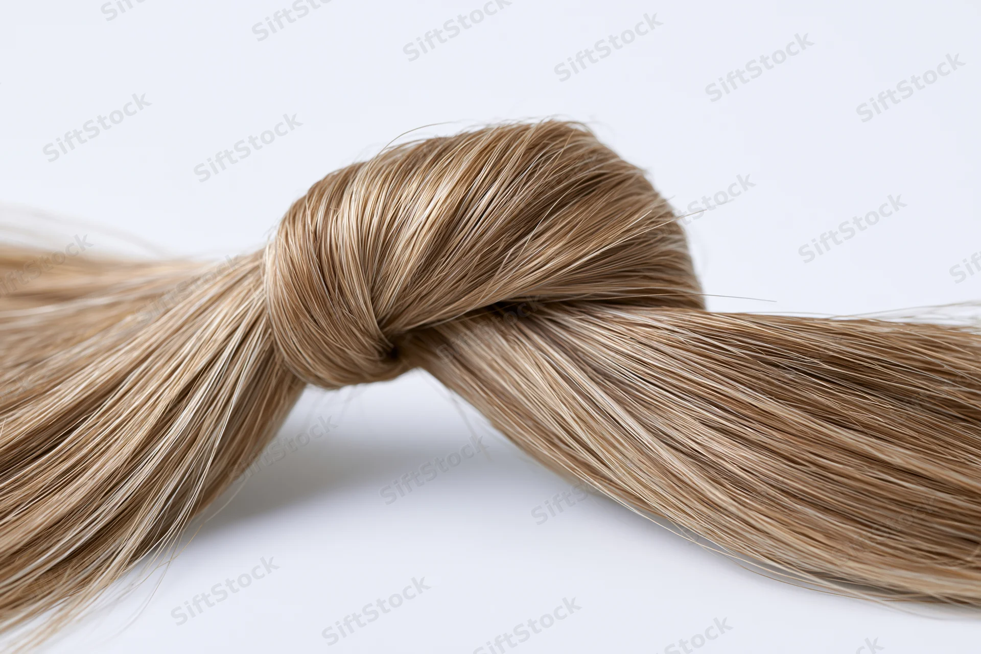 Twisted lock of straight light brown hair forming a loose knot on white background