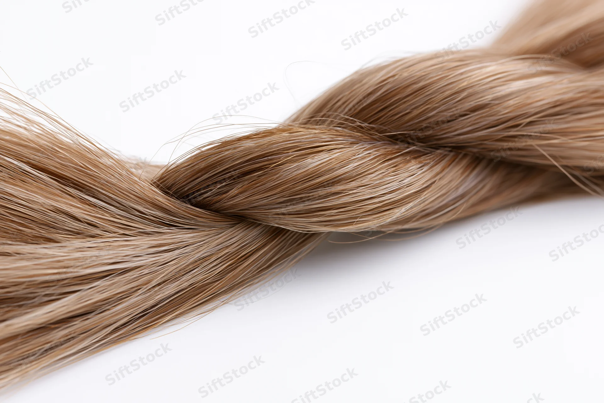 Twisted lock of straight light brown hair forming a loose braid on white background