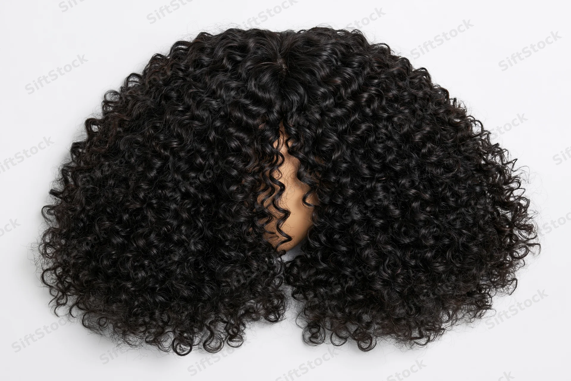 Voluminous black curly wig displayed flat on white background
