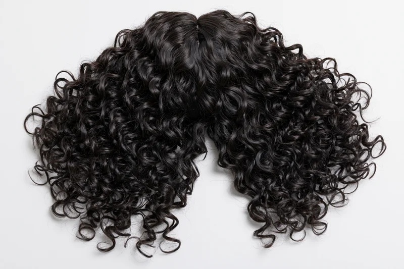 Black curly wig laid flat on white background