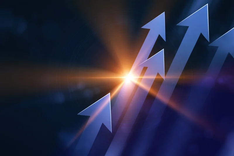 Multiple blue arrows pointing upward in a dark abstract background with a glowing light at the center