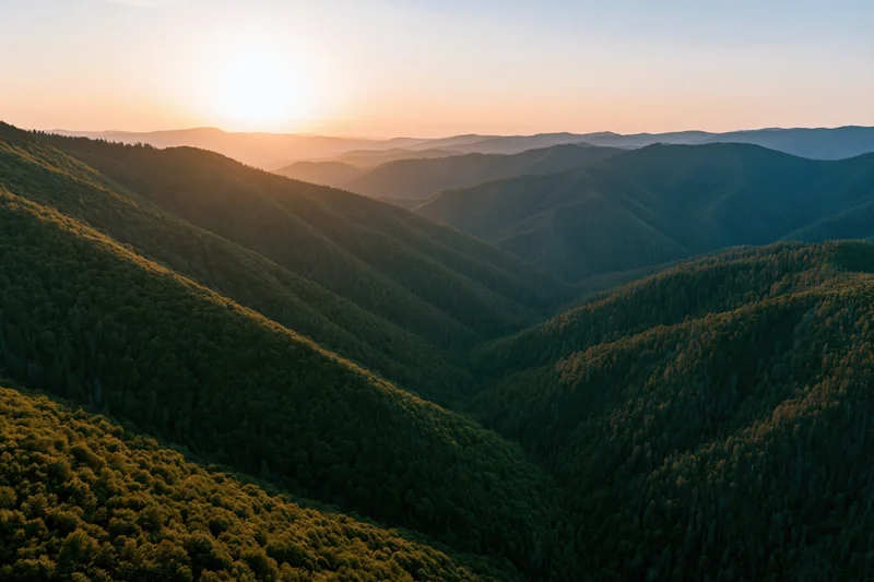 Aerial view of layered green mountain ridges at sunset