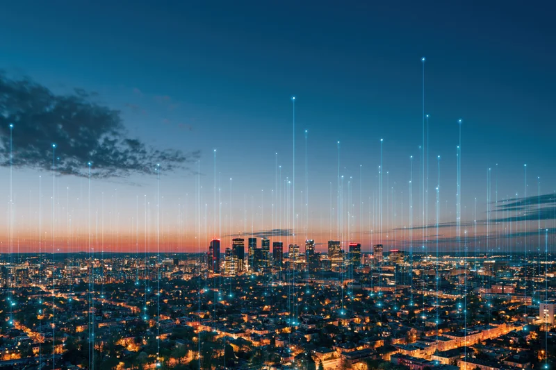 Aerial view of a dense city skyline at blue hour dusk with digital signal lines extending upward from buildings