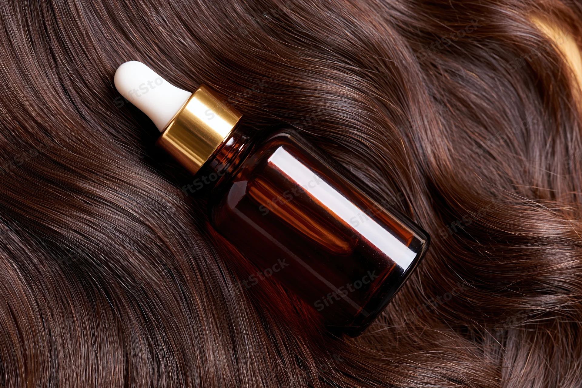Amber glass dropper bottle resting on lustrous brown hair