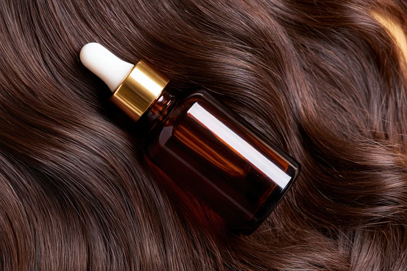 Amber glass dropper bottle resting on lustrous brown hair