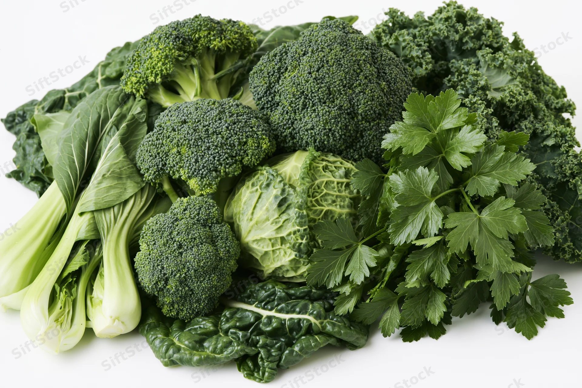 Assorted fresh green vegetables piled together on white background