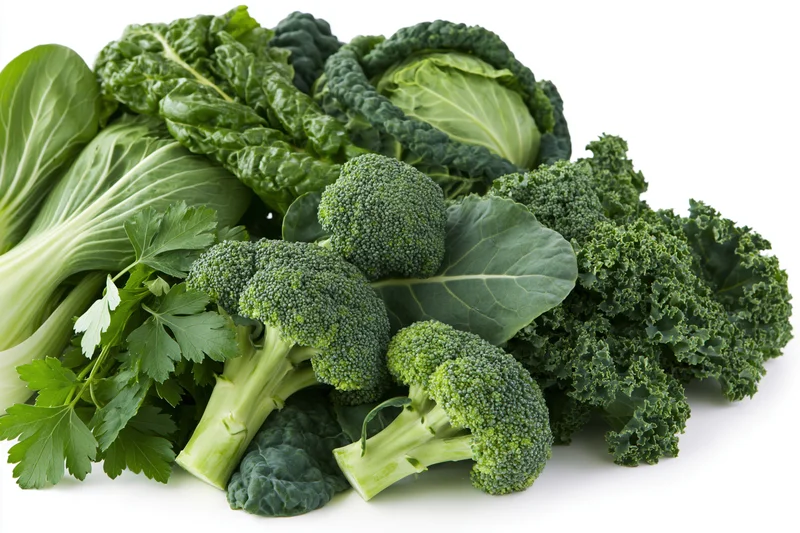 Assorted fresh green vegetables piled together on white background