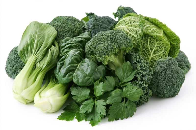 Assorted fresh green vegetables piled together on white background