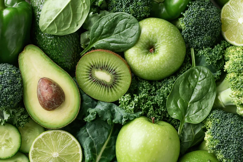 Assorted green fruits and vegetables arranged densely in a flat lay overhead view