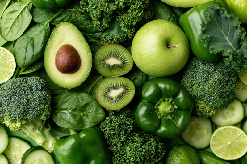 Assorted green fruits and vegetables arranged densely in a flat lay top view
