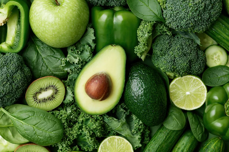 Assorted green fruits and vegetables arranged densely in a flat lay top view