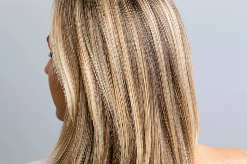Back of a woman’s head showing long straight blonde hair with highlights
