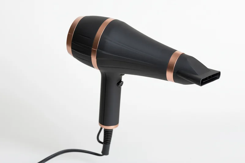 Black and rose-gold hair dryer with concentrator nozzle on white background