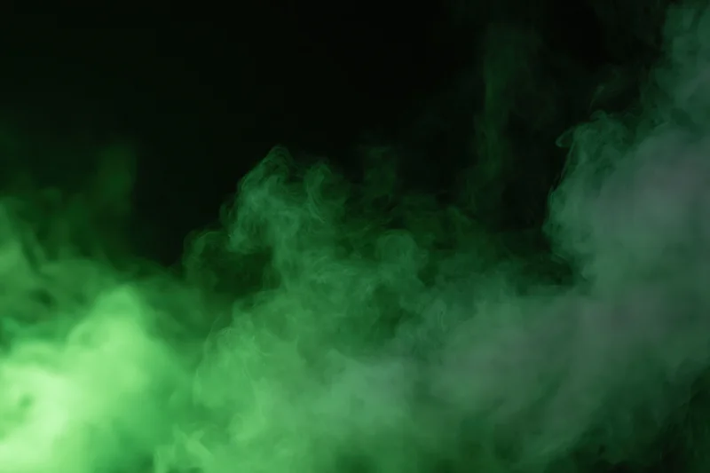 Green smoke drifting upward against a dark background