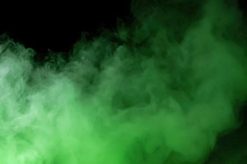 Green smoke drifting upward against a dark background
