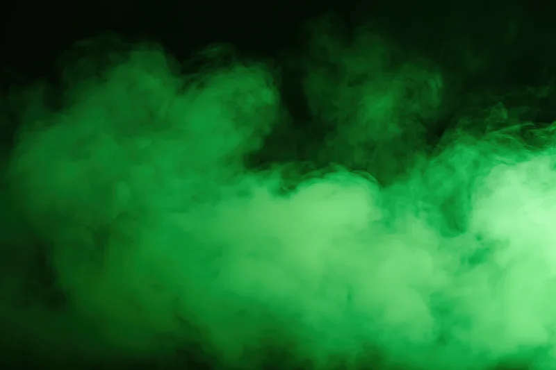 Green smoke drifting upward against a dark background
