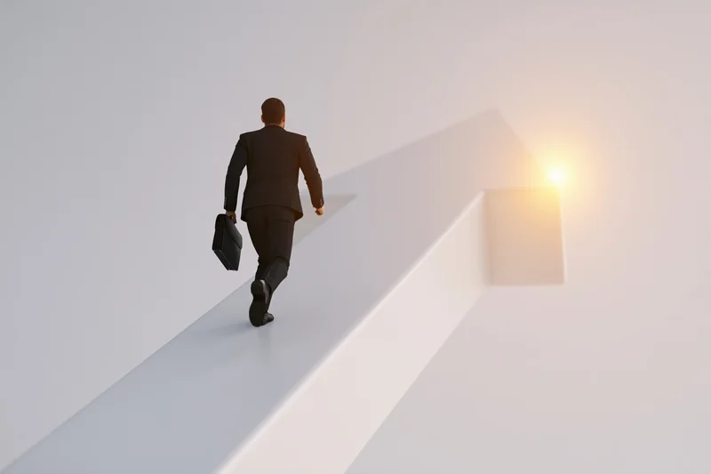 Businessman in dark suit running with briefcase up white upward path toward light