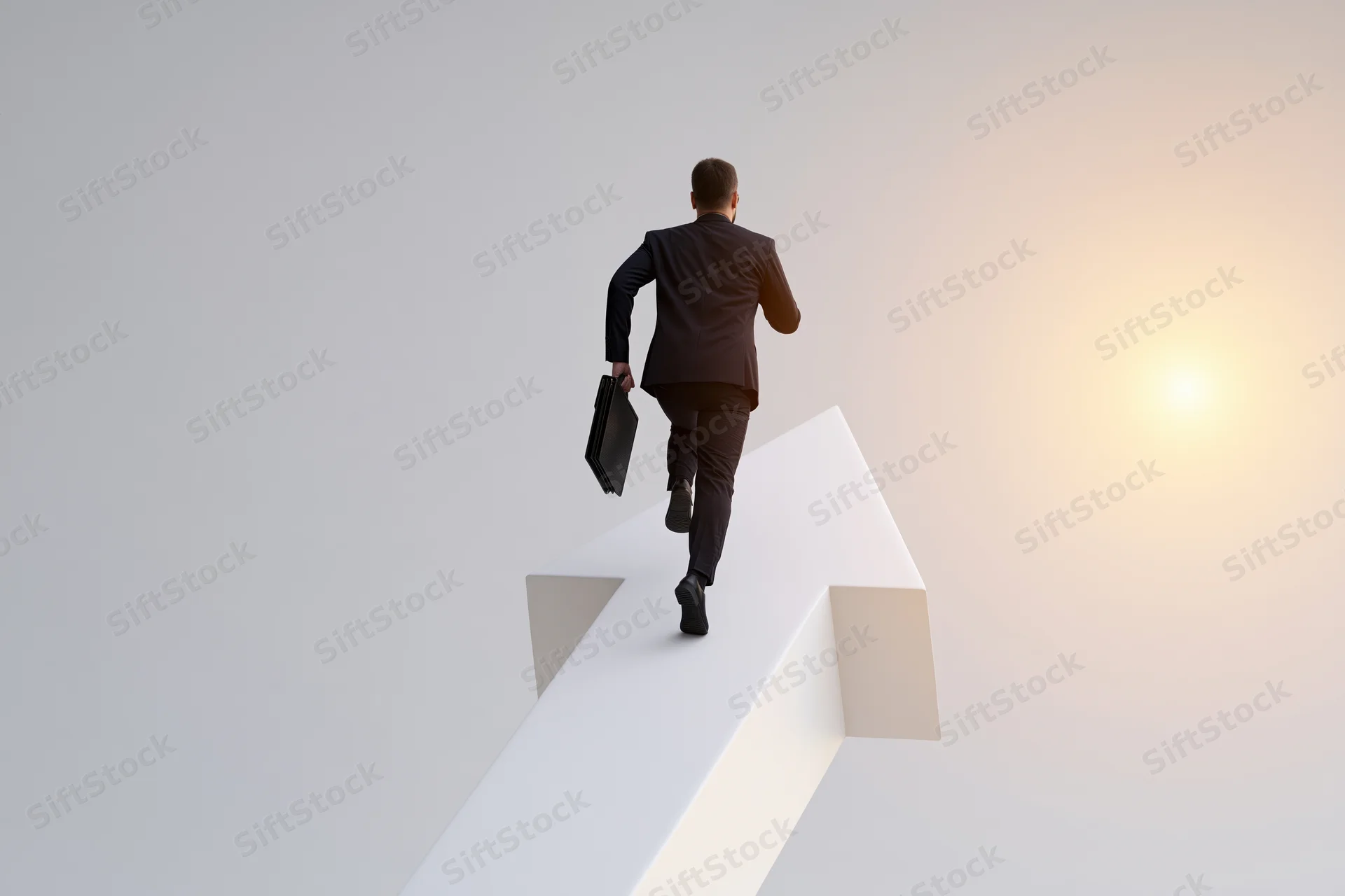 Businessman in dark suit running up white arrow toward sunrise